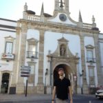 Kyle, standing in front of an old decorative portal in the city wall of Faro, Portugal